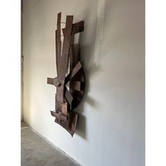 a wooden sculpture hanging on the side of a wall next to a white painted wall