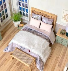 a bed with white fur on it in a room next to a table and potted plant