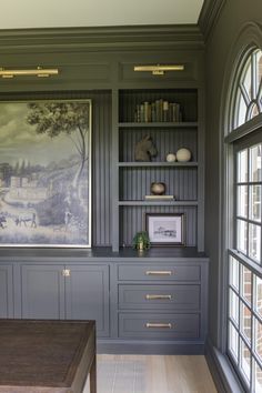 a room that has some bookshelves and cabinets in it with pictures on the wall