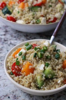 two bowls filled with rice and vegetables on top of a marble counter next to each other