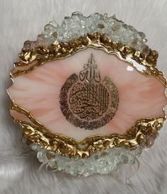 a pink and gold plate with an arabic calligraphy in the center on top of it