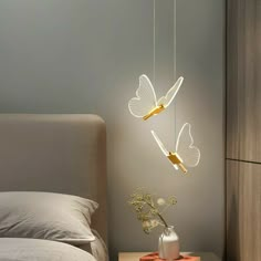 a bedroom with a bed, nightstand and two butterflies hanging from it's sides