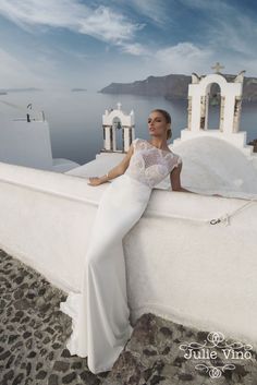 a woman in a white dress leaning against a wall