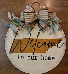 a wooden sign that says welcome to our home with two bows on the front and back