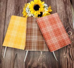 three napkins with sunflower on them sitting next to each other in front of a wooden table