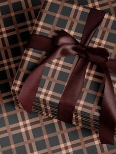 two wrapped gift boxes with brown ribbon on checkered fabric, one is empty and the other has a bow