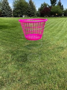 a pink basket sitting on top of a lush green field