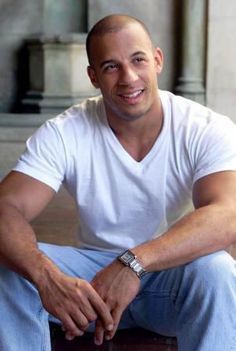 a man in white shirt and blue pants sitting on top of a wooden box with his hand on the chest