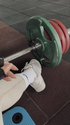 a person is holding a barbell in their hand while standing on the ground with other equipment