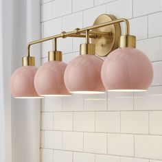 a bathroom light with five pink balls hanging from it's arm in front of a white tiled wall