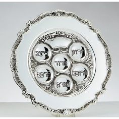 an ornate silver plate with eight plates in the center and hebrew writing on it, set against a white background