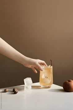 a person reaching for an apple in a glass with ice cubes on the table