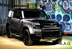 a black and silver suv parked in front of a wall with graffiti written on it