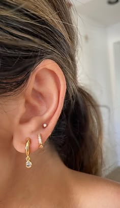 a close up of a person wearing gold earring with two small diamonds on them