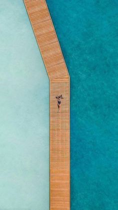 an aerial view of a dock with a person standing on it and looking down at the water