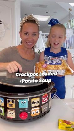 a woman and girl standing in front of a crock pot with food on it