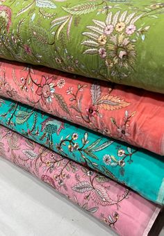 four different colored fabrics are stacked on top of each other, one is green and the other is pink