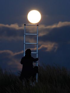 a person climbing up a ladder to the moon