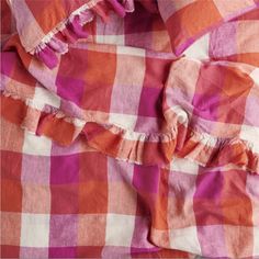 an orange and pink checkered shirt with ruffles on the bottom, sitting on a bed