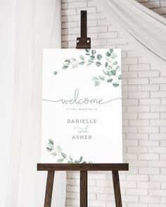 a welcome sign on an easel in front of a brick wall with white drapes