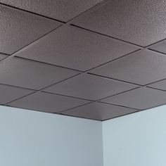 an empty room with white walls and square ceiling tiles on the ceiling, in front of a blue wall