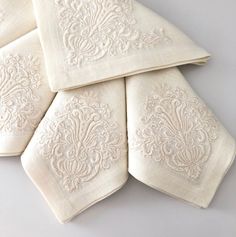 four white embroidered napkins stacked on top of each other