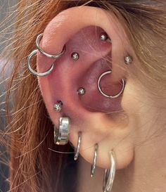 a woman's ear with multiple hoops and piercings on the side of her ear