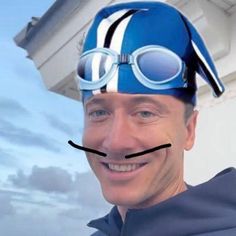 a man wearing a blue hat and goggles on top of his head with a nose ring