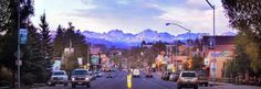 cars are driving down the street in front of mountains