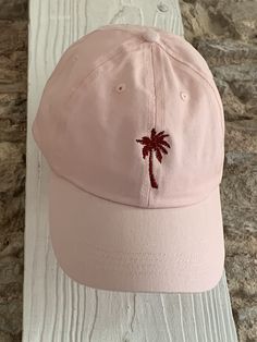 Description: Escape to a tropical paradise with our Personalised Embroidered Palm Tree Cap. This cap is a must-have accessory for beach lovers and nature enthusiasts, providing a stylish way to embrace the laid-back vibes. The front of the cap features a beautifully embroidered palm tree design, instantly transporting you to sandy beaches and sunny days. Choose from a variety of cap colours, including beige, mint green, pale blue, navy, pink, lemon, and black, to match your personal style. Personalisation: Make this cap truly unique by customising the colour of the front embroidery. Choose your preferred colour from our available options to create a cap that perfectly reflects your tropical paradise. Additionally, you can add your name or initials with our optional back embroidery. Simply Trendy Curved Bill Dad Hat For Beach, Adjustable Beach Baseball Cap With Embroidered Logo, Cotton Baseball Cap For Beach, Trendy Cotton Baseball Cap For Vacation, Trendy Vacation Dad Hat Snapback, Trendy Adjustable Dad Hat For Beach, Trendy Dad Hat Baseball Cap For Vacation, Trendy Snapback Dad Hat For Vacation, Trendy Adjustable Dad Hat For The Beach