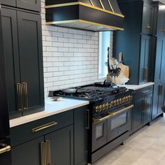 a kitchen with black cabinets and gold trim on the stove top, oven hood and range