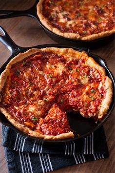 two deep dish pizzas sitting on top of a wooden table next to each other