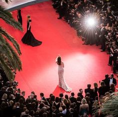 a woman standing on top of a red carpet in front of a group of people