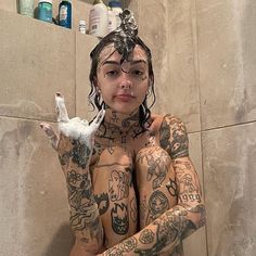 a woman with tattoos on her body is holding a bird in front of her face