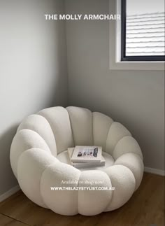 a white chair sitting in the corner of a room with a book on top of it