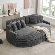 a large gray couch sitting on top of a living room floor next to a window