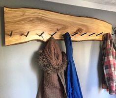 a coat rack with coats hanging from it's hooks and two jackets hanging on the wall