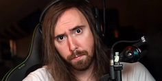 a man with long hair and beard sitting in front of a microphone looking at the camera