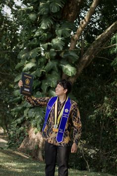 a man in a blue and gold sash holding up a book