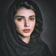 a woman wearing a black shawl and looking at the camera with a serious look on her face