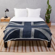 a bed with a blue and white blanket on it next to a potted plant