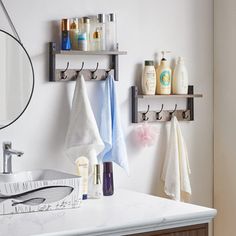 a bathroom sink with two towels hanging on the wall and soaps in front of it