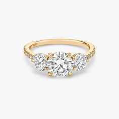 three stone engagement ring in yellow gold with diamonds on the sides and an oval diamond center