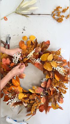 someone is making a wreath out of fake leaves