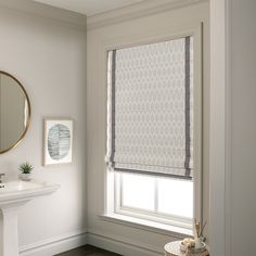 a bathroom with a sink, mirror and window coverings on the windows sill