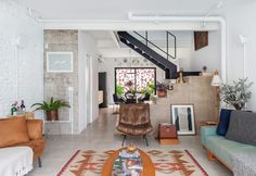 a living room filled with furniture and a stair case in the back drop off wall