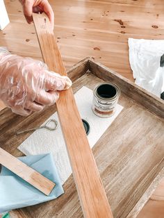 a person in white gloves painting a wooden frame