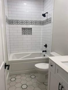 a white toilet sitting next to a bath tub in a bathroom with black and white tile