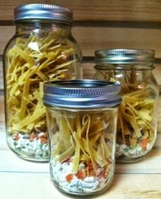 three jars filled with food sitting on top of a wooden table