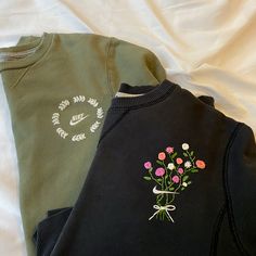 two sweatshirts with flowers on them laying next to each other